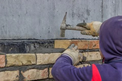 Using mason hammer to tap brick into position Stock Photos