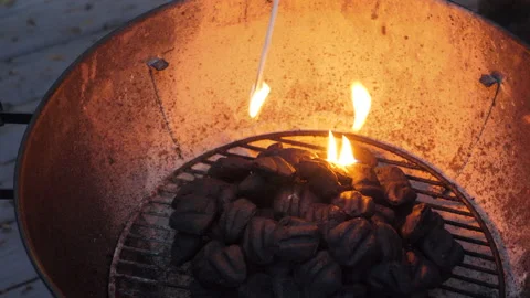 Using a match to ignite charcoals in a barbecue grill Stock Footage 154759131