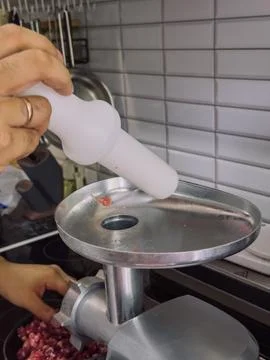 Using a meat grinder pusher to safely press raw meat into electric meat grinder Photos