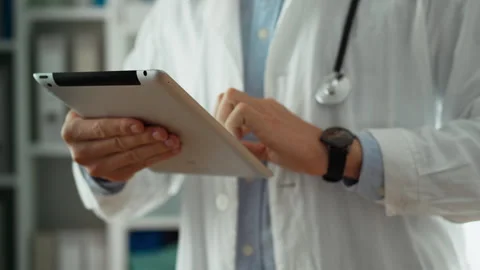 Using. A medical specialist in a white coat works with a tablet in the offic Stock Footage 253183250