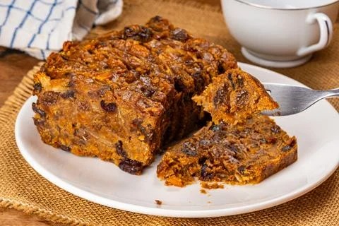 Using metal fork picking a piece of dried fruitcake up. Stock Photos