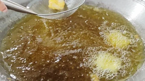 Using a metal mesh strainer to scoop up food from hot frying oil. Stock Footage 342686520