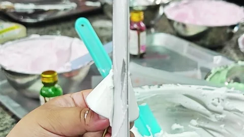 Using a metal spatula to scrape white cake cream frosting. Vídeo Stock 344745055