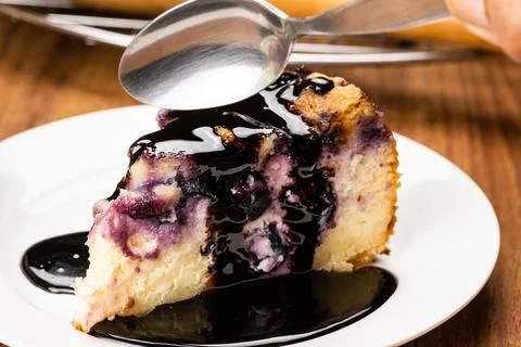Using metal spoon taking a bite of homemade blueberry and crumble cheesecake. Stock Photos