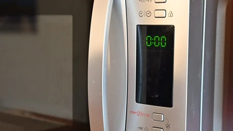 Using the microwave oven. Close up shot of the timer. Caucasian man's hands put Stock Footage 125856897