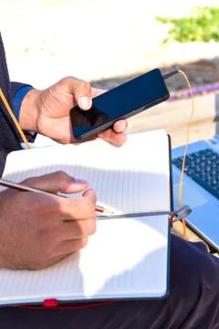 Using mobile devices cellphone and laptop outdoors. Stock Photos
