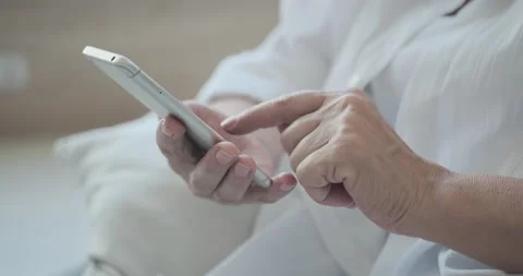 Using mobile phone applications, close up on a mature elderly woman. Stockbeeldmateriaal 159978052