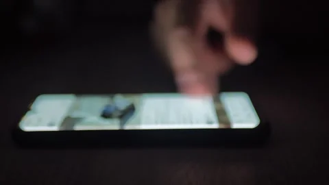 Using a mobile phone in a dark room. Human hands scroll through photos of cars Stock Footage 258109302