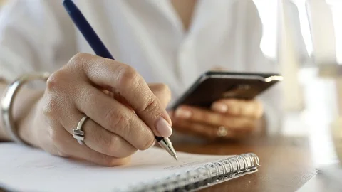  Using a mobile phone. A girl writes information from a smartphone in a notebook Video stock 110722457
