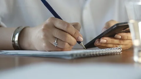  Using a mobile phone. A girl writes information from a smartphone in a notebook Video stock 110722487