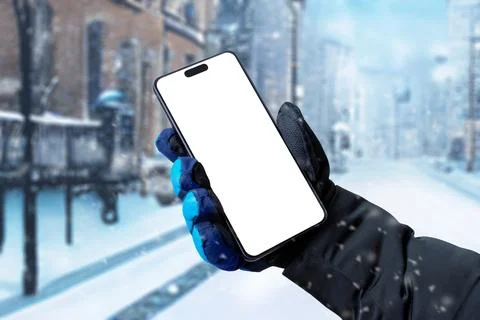 Using a mobile phone on the street while it is snowing. Isolated display for  Stock Photos