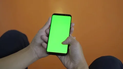 Using mobile smart phone with green screen in library. Thumb scrolling display Stockbeeldmateriaal 80555081