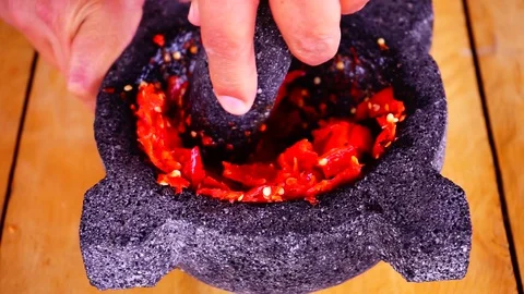 Using a morter to grind chilli peppers Stock Footage 129403862