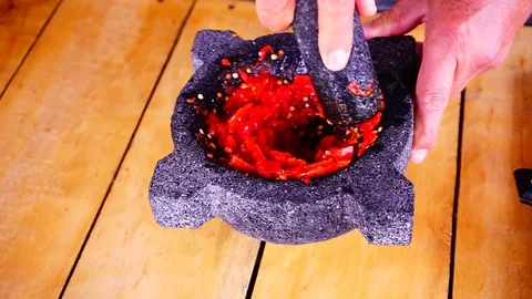 Using a morter to grind red hot chilli peppers Stock Footage 129402543