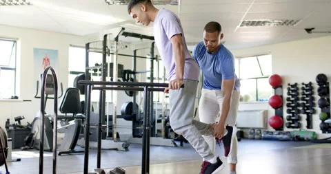 Using parallel bars for rehabilitation exercise, man with disability supported Stock-Footage 300148205