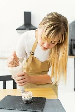 Using a pastry bag, the pastry chef makes cupcakes. Stock Photos