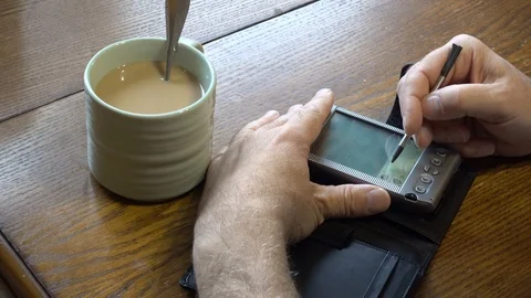 Using a PDA while drinking a cup of Coffee Stock Footage 88565464