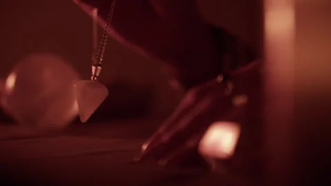 Using a pendulum for divination at candlelit spiritual table Stock Footage 306637651