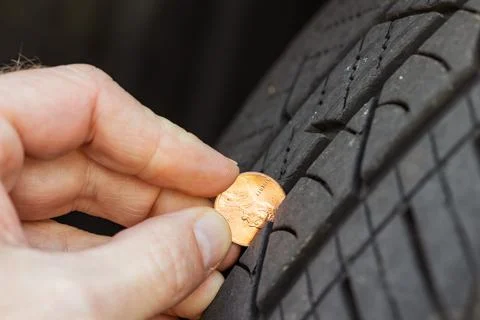 Using a penny to check tread depth on a tire Stock Photos