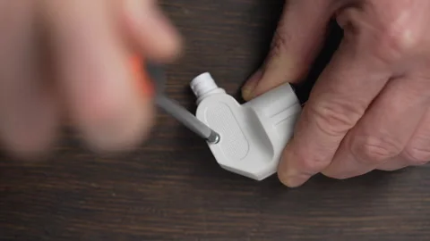 Using a Phillips screwdriver, loosen the screw on white electrical power plug Stock Footage 295864685