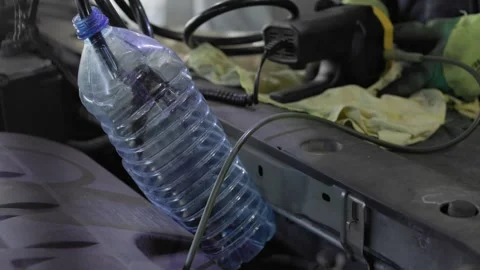 Using a plastic bottle in the mechanics workspace for motor oil extraction Stock Footage 305770473