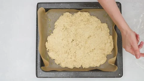 Using a plastic wrap chef unfurl pizza dough onto a baking pan.  Video stock 148016304