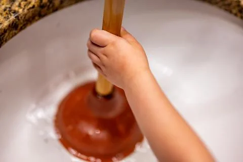 Using a plunger on a bathroom sink plugged with Hair and scum in a pool of Foto stock