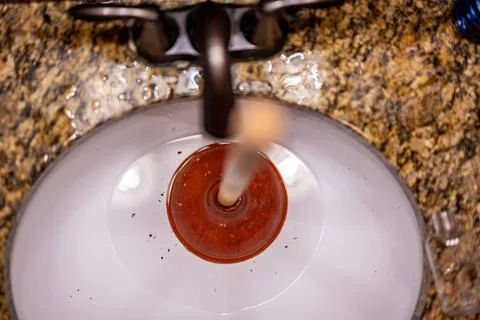 Using a plunger on a bathroom sink plugged with Hair and scum in a pool of Foto stock