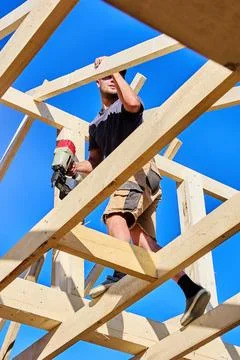 Using pneumatic framing nailer, young worker fastens wooden boards during t.. Stock Photos