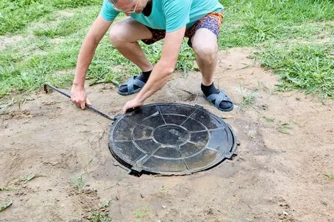Using pry bar to lift polymer manhole cover made of composite materials. Foto stock