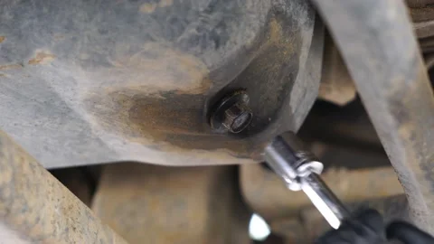 Using a ratchet and socket to remove an oil pan plug on a truck's Stock Footage 180374472
