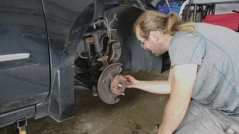 Using ratchet wrench to loosen nuts in bearing assembly in sedan front wheel Video stock 129798766