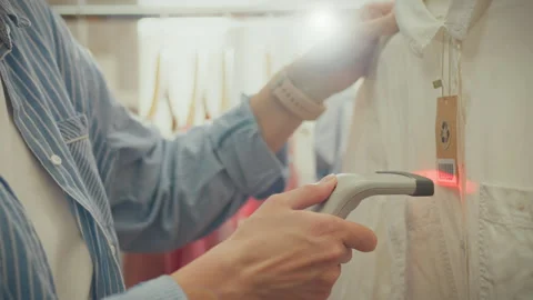 Using a red laser scanner, an Asian worker in a clothing store scans barcode Stock Footage 270429277