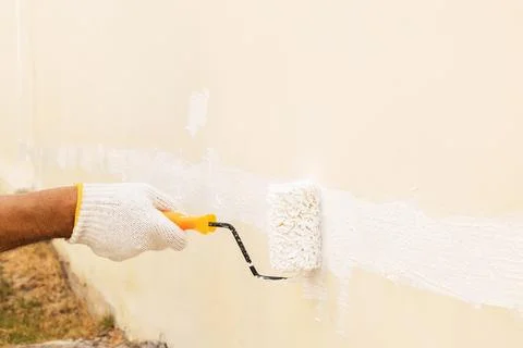Using a roller for painting white color on the concrete wall. Stock Photos