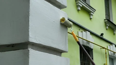 Using a roller, they paint a white wall outside 库存影片 306153042