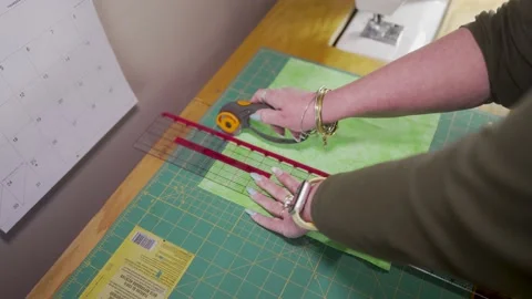 Using a rotary fabric cutter to slice cloth into shapes to make a quilt Stock Footage 171453519
