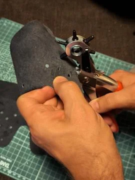 Using a rotary leather hole punch on a black material. Fotos Stock