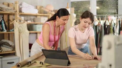 Using ruler and chalk, women tailor draws dress diagram scheme on paper Stock Footage 341784013