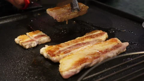 Using scissor to cut thick pork belly at Korean barbecue restaurant Stock Footage 142145093