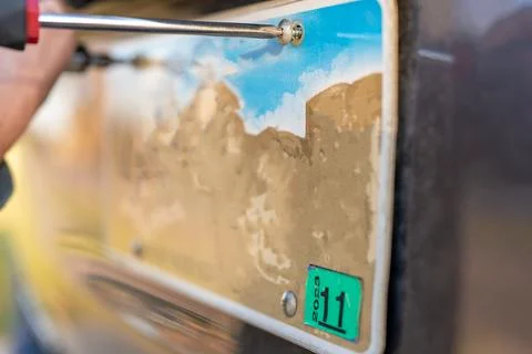 Using a screw driver to remove and replace a vehicle rear license plate. Foto stock