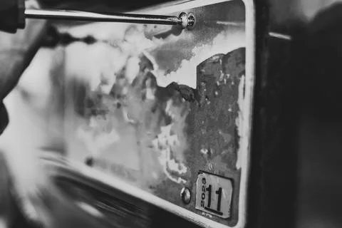 Using a screw driver to remove and replace a vehicle rear license plate. Foto stock