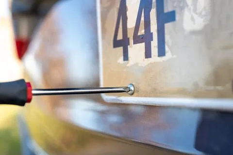 Using a screw driver to remove and replace a vehicle rear license plate. U... Foto stock
