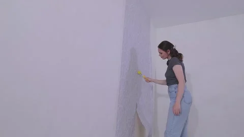 Using a seam roller to securely adhere the edges of the wallpaper to the wall Stock Footage 332245645