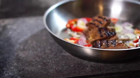 Using silicone shovel to mix fried beef steak meat with fresh vegetables red Stock Footage 105457675
