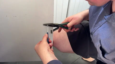 Using small metal hand tools for screw removal in a dated kitchen Stock Footage 295460741