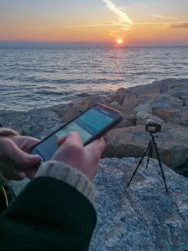 Using Smart Phone and Camera on Seaside out of Focus Stock Photos