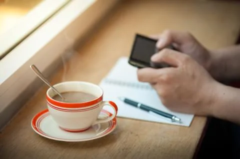 Using smart phone with coffee cup Stock Photos
