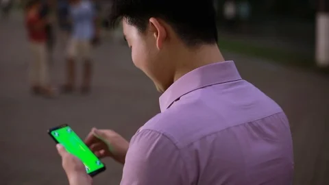 Using smart phone on in the Park by Asian boy close up-green screen Stock Footage 93257078