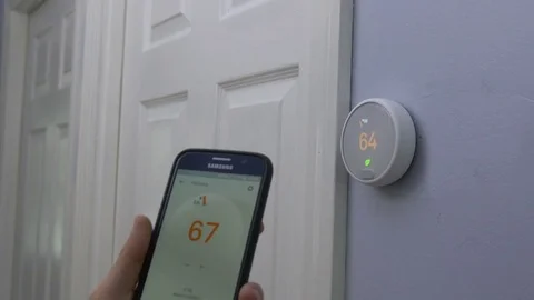 Using Smart Phone to Turn Up Smart Thermostat Temperature Vídeo Stock 83649832