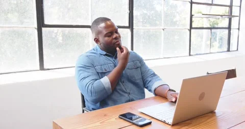 Using smartphone and laptop, African American man multitasking efficiently at 스톡 동영상 345715712